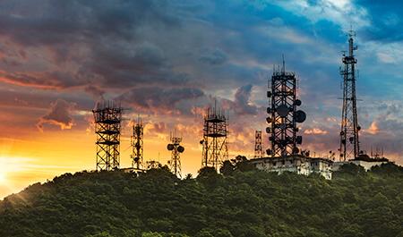 夕阳背景下与山的通信和电信的天线塔和中继器.